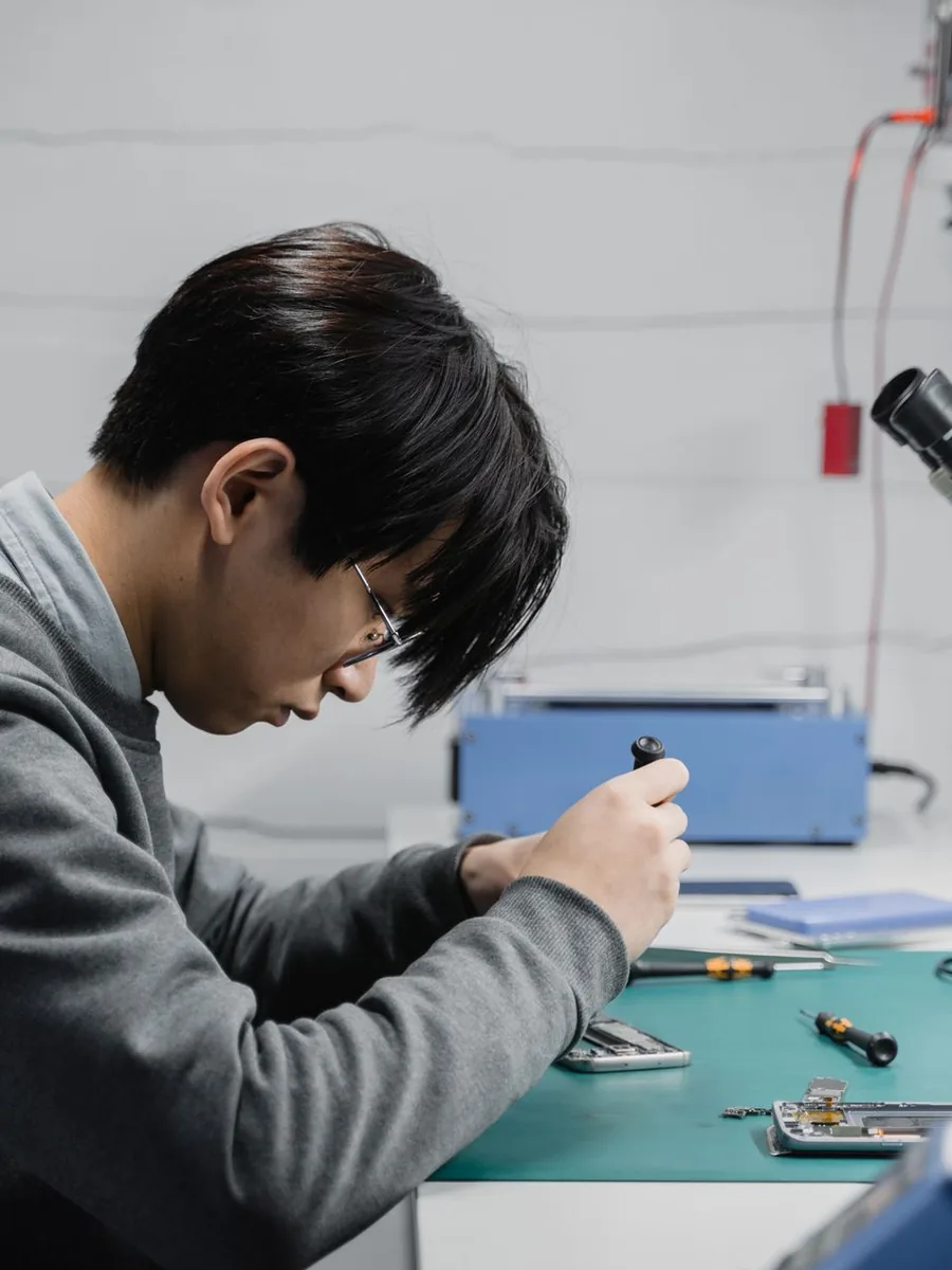 Técnico analisando a placa de um celular no microscópio